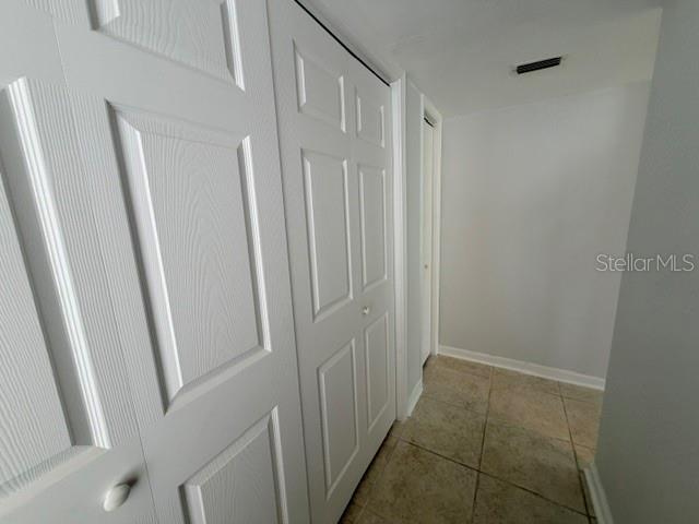 A hallway features white paneled closet doors, light-colored tile flooring, and neutral wall paint — 5521 BAY BOULEVARD UNIT 101, PORT RICHEY, FL