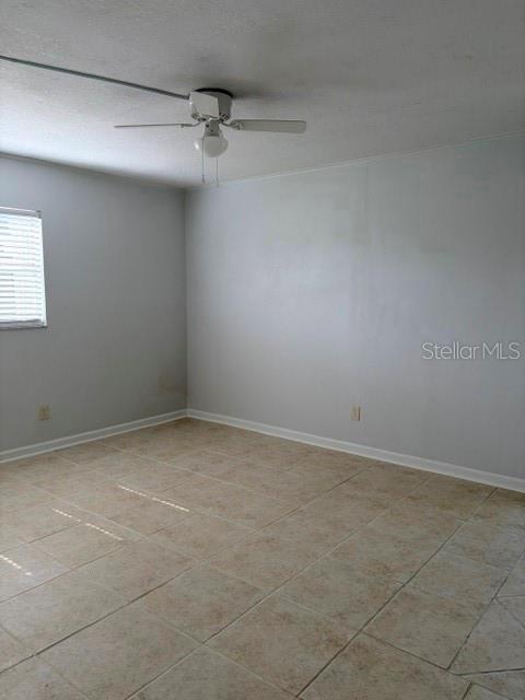 An empty room features light-colored tile flooring, gray walls, and a ceiling fan — 5521 BAY BOULEVARD UNIT 101, PORT RICHEY, FL