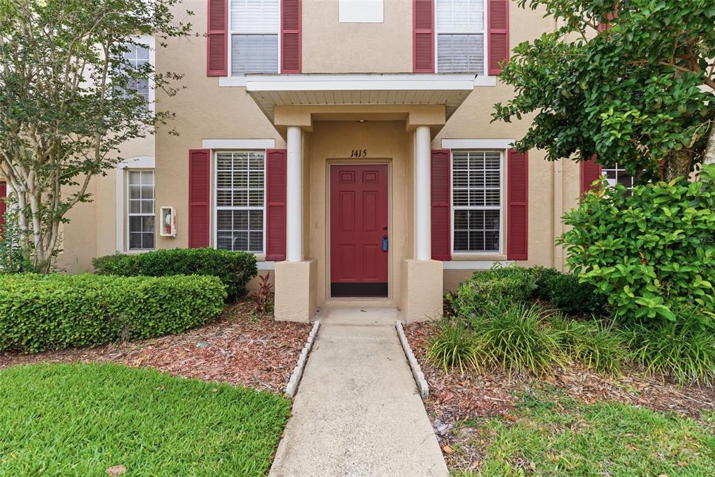 The exterior of a two-story townhouse features a red front door and red shutters — 1415 SEDGWICK DRIVE, WESLEY CHAPEL, FL