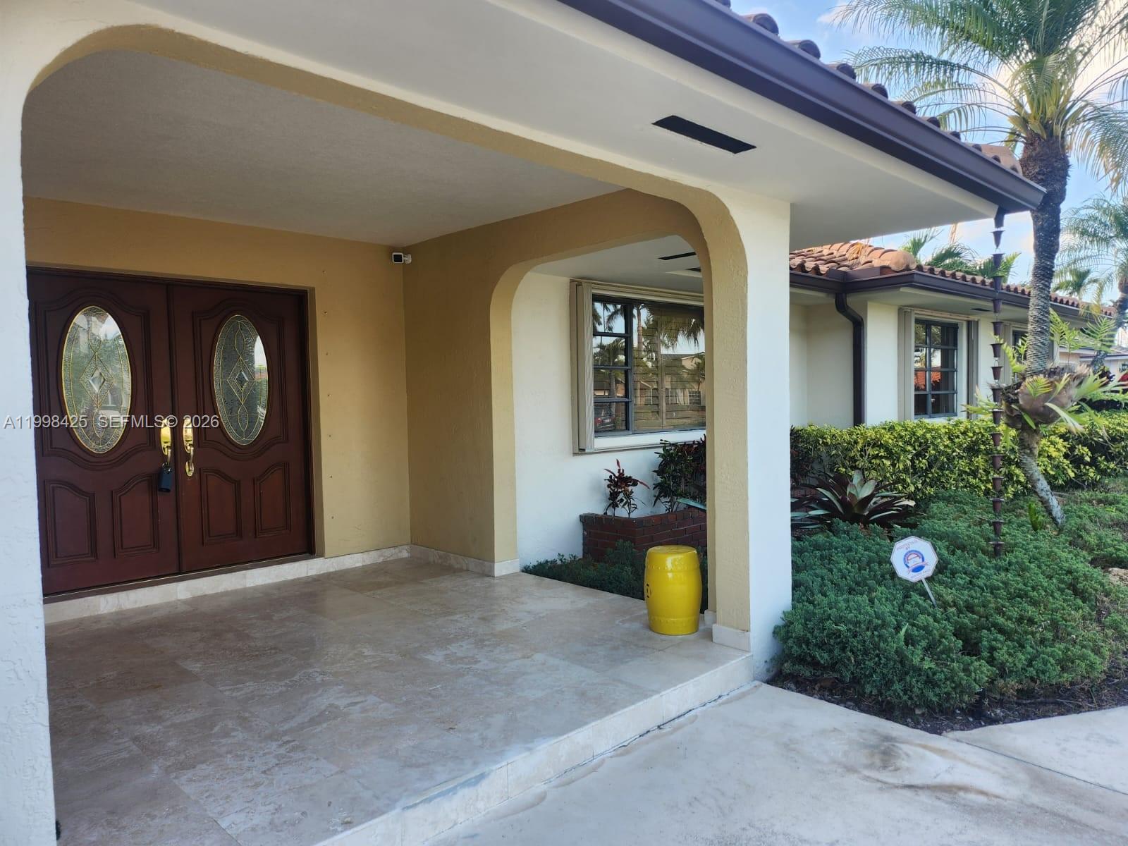 The exterior of a house features a covered stone porch, double doors, and landscaping — 2980 SW 111th Ave, Miami FL 33165, MIAMI, FL