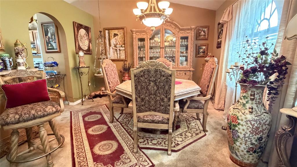 A formal dining room features a wooden table, patterned chairs, a hutch, and decorative rugs — 3690 WELLINGTON PLACE, BARTOW, FL