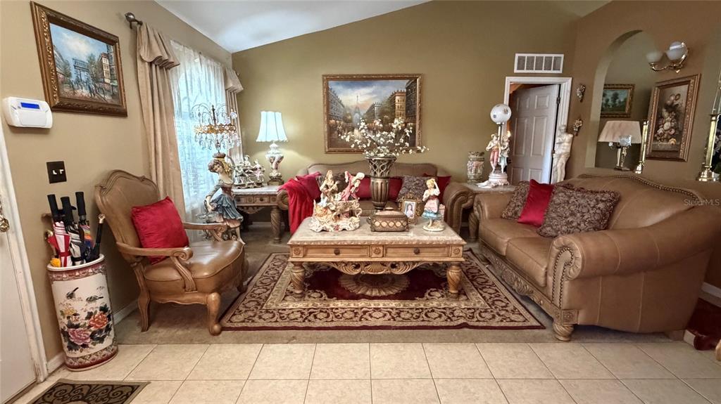 A living room features tan leather furniture, a central coffee table, and ornate decorative accents — 3690 WELLINGTON PLACE, BARTOW, FL
