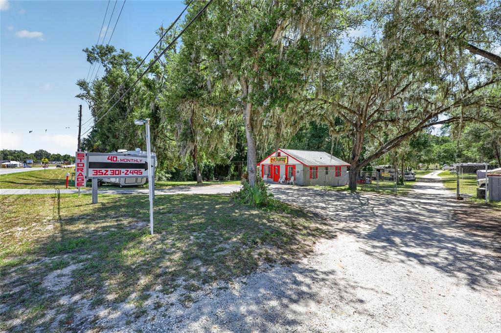 A small building with red trim sits on a gravel lot under large oak trees — 3362 N CARL G ROSE HIGHWAY, HERNANDO, FL