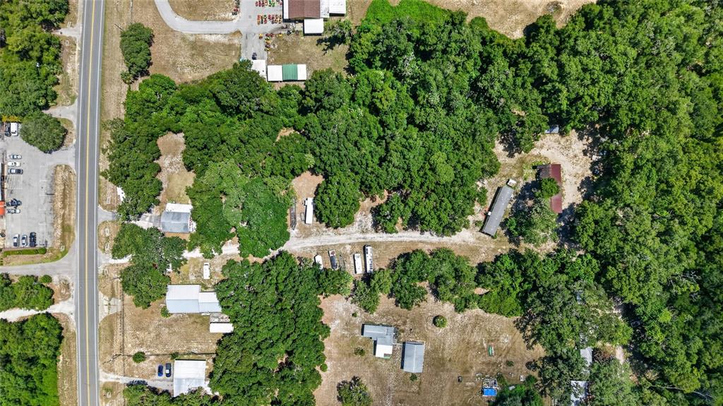 An aerial view shows a wooded property with several small buildings, trailers, and a road — 3362 N CARL G ROSE HIGHWAY, HERNANDO, FL