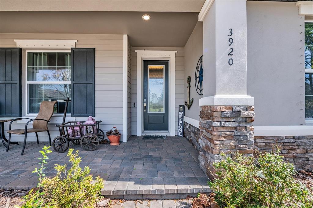 A front porch features a stone-based pillar, a dark door, and a decorative wagon — 3920 NIGHT STAR TRAIL, ODESSA, FL