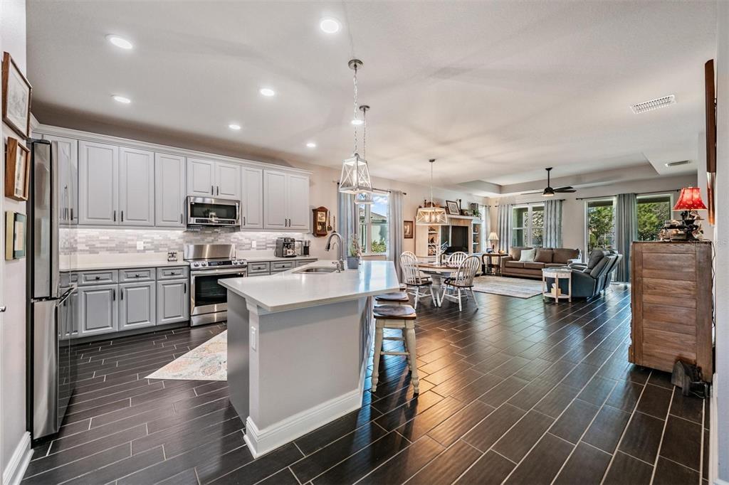 A kitchen with light gray cabinets and a central island overlooks an open living area — 3920 NIGHT STAR TRAIL, ODESSA, FL