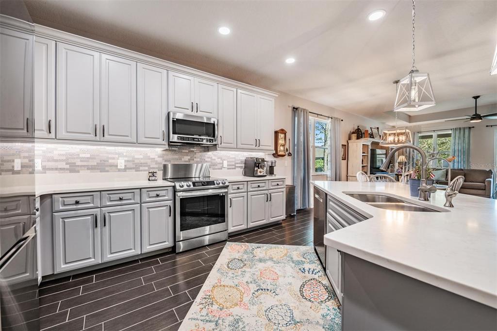 A kitchen with light gray cabinets, stainless steel appliances, white countertops, and dark tile flooring — 3920 NIGHT STAR TRAIL, ODESSA, FL