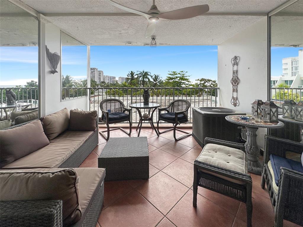 A covered balcony features tiled flooring, outdoor furniture, and a view of trees and buildings — 6165 AVE. ISLA VERDE UNIT 369, CAROLINA, PR