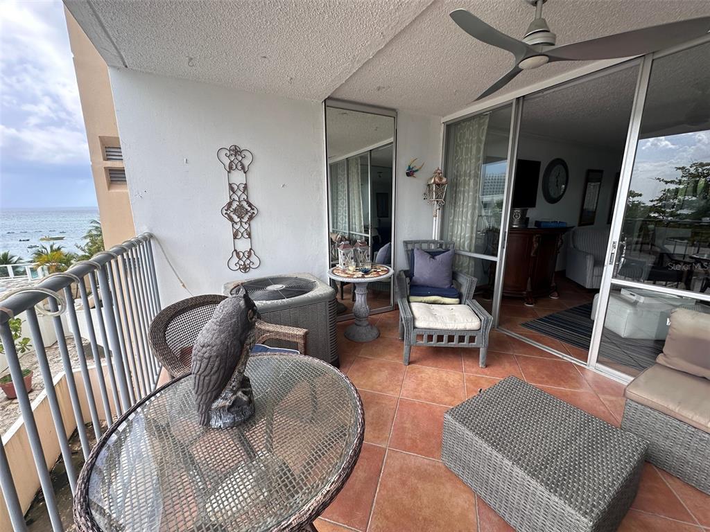 A balcony with tiled flooring, patio furniture, an air conditioning unit, and ocean views — 6165 AVE. ISLA VERDE UNIT 369, CAROLINA, PR