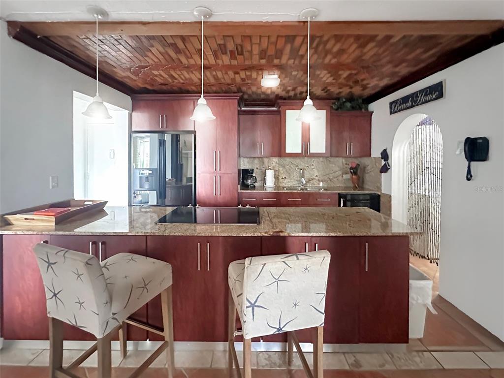 A kitchen features dark wood cabinetry, granite countertops, a large island, and a wood-paneled ceiling — 6165 AVE. ISLA VERDE UNIT 369, CAROLINA, PR