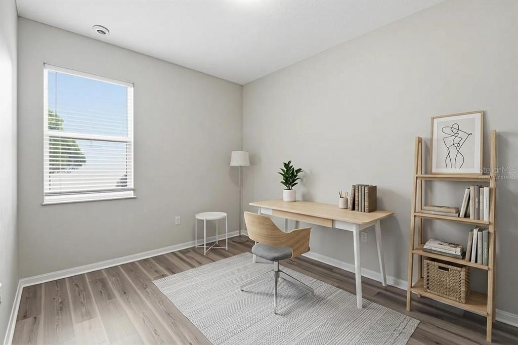 A home office with light wood flooring, a desk, a chair, and a wooden bookshelf — 427 FERN GULLEY DRIVE, SEFFNER, FL