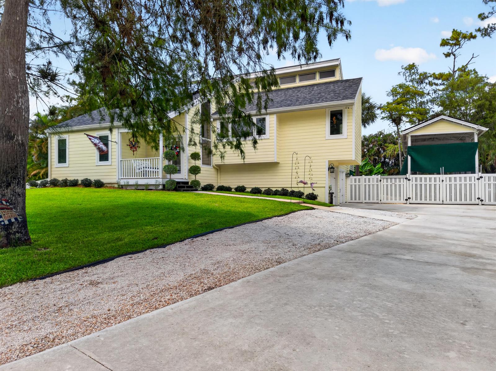 A yellow two-story house with a gravel driveway, front porch, and a detached carport — 13074 La Mirada Circle, Wellington FL 33414, WELLINGTON, FL