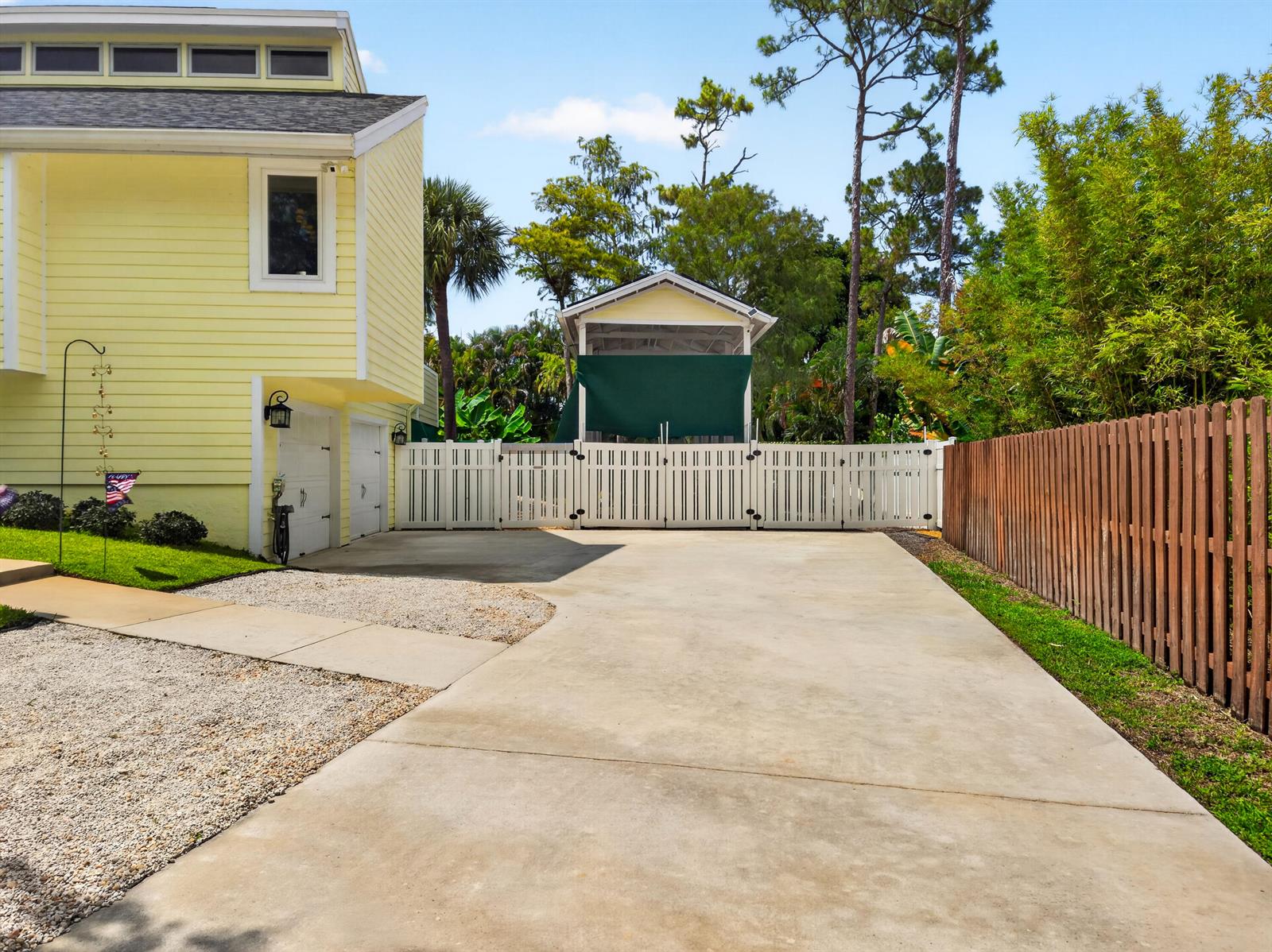 A yellow house with a concrete driveway, white fence, and a detached covered structure — 13074 La Mirada Circle, Wellington FL 33414, WELLINGTON, FL