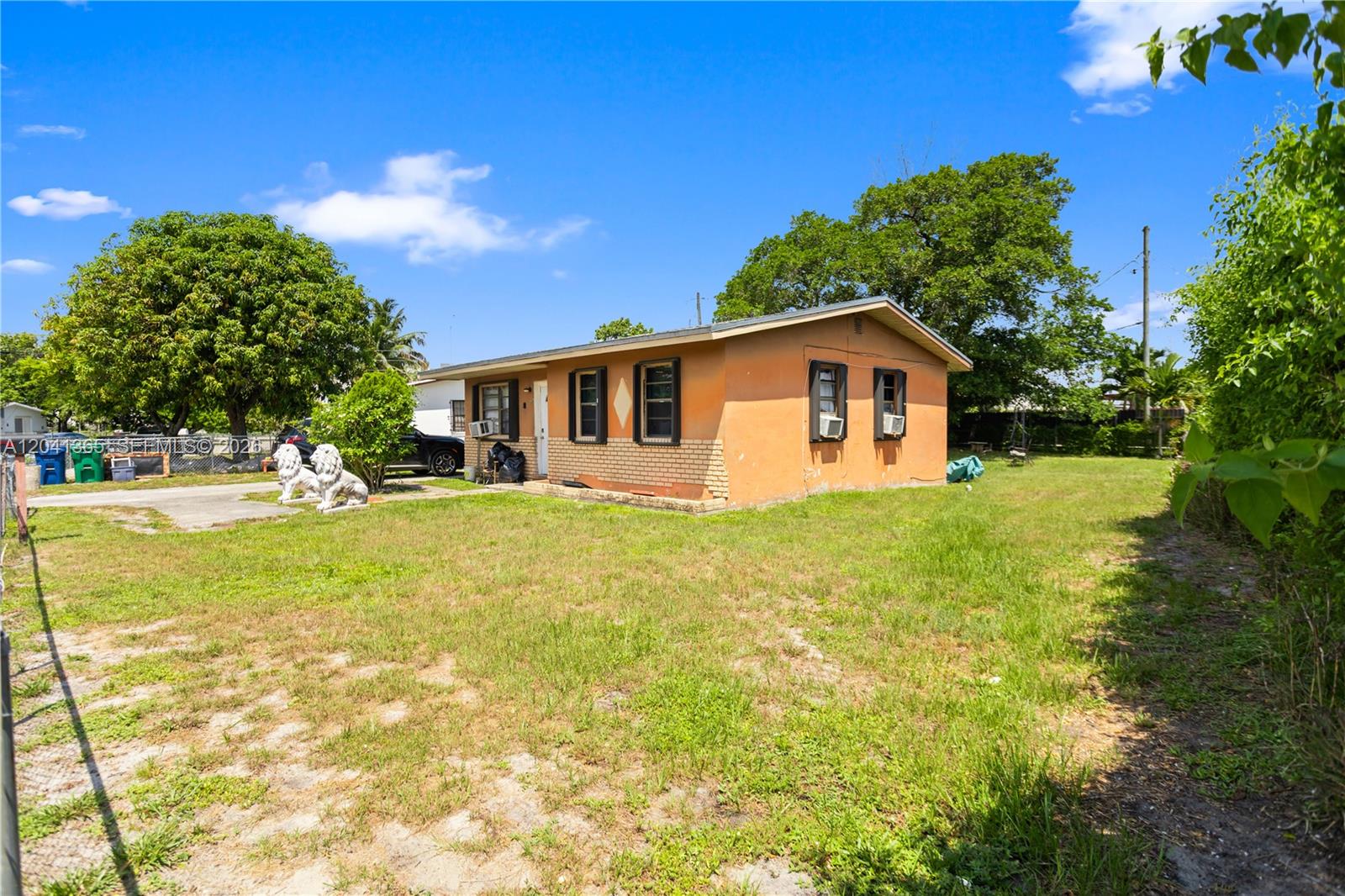 A single-story orange house with a brick base sits on a grassy lot — 555 Harem Ave, Opa-Locka FL 33054, OPA-LOCKA, FL