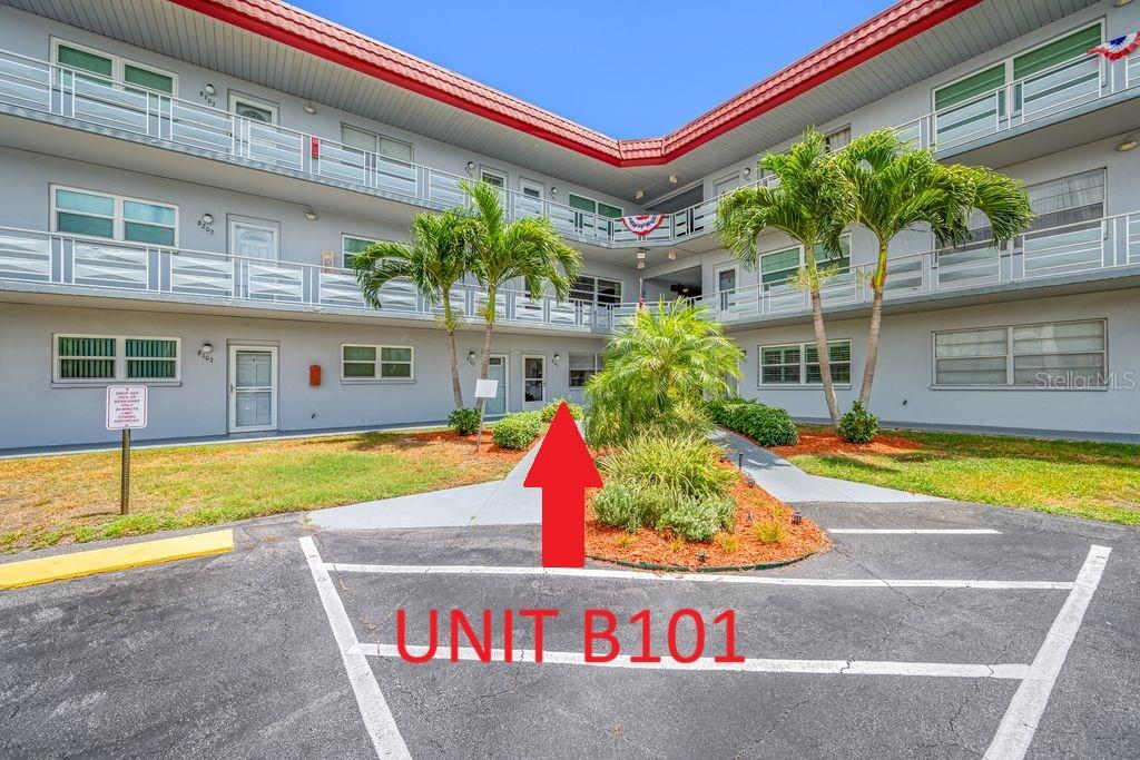 The exterior view shows a multi-story apartment building with a parking space marked for unit B101 — 5660 80TH STREET N UNIT B101, ST PETERSBURG, FL