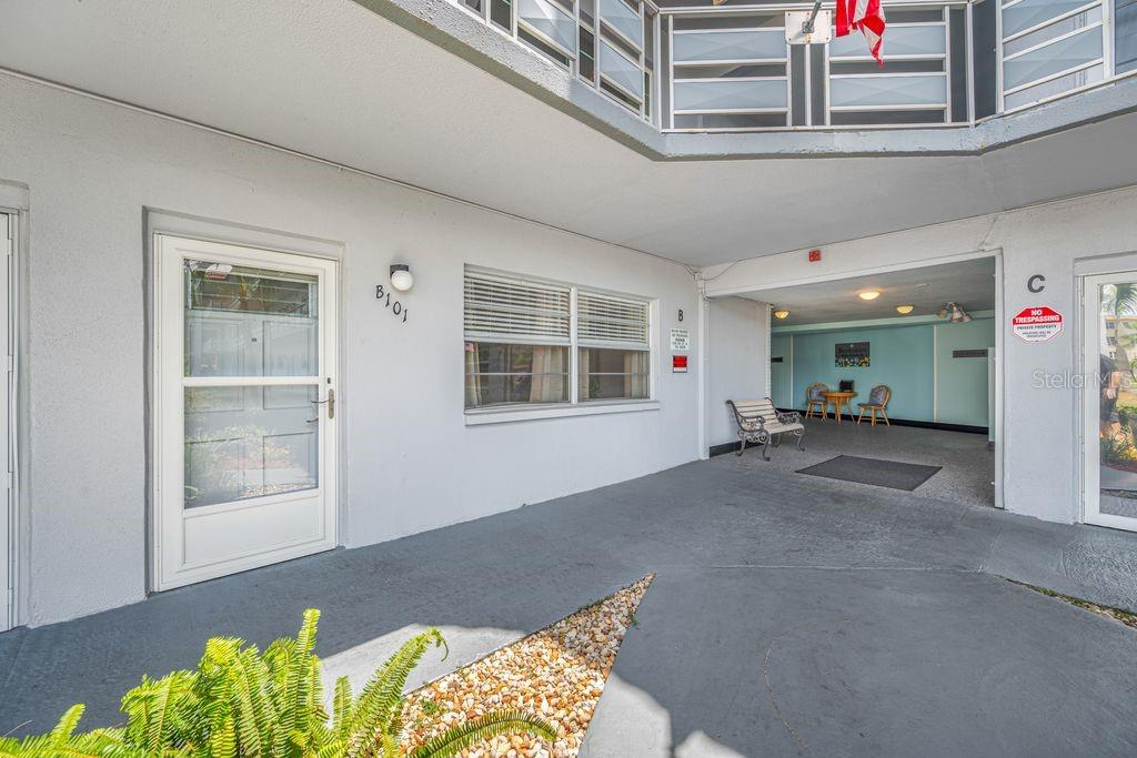 An outdoor walkway leads to a building entrance with a white door labeled 101 — 5660 80TH STREET N UNIT B101, ST PETERSBURG, FL
