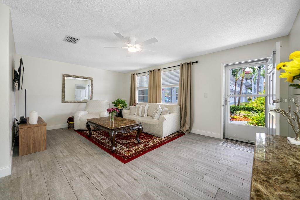 A living room features light tile flooring, a red area rug, and a glass-paned door — 5660 80TH STREET N UNIT B101, ST PETERSBURG, FL