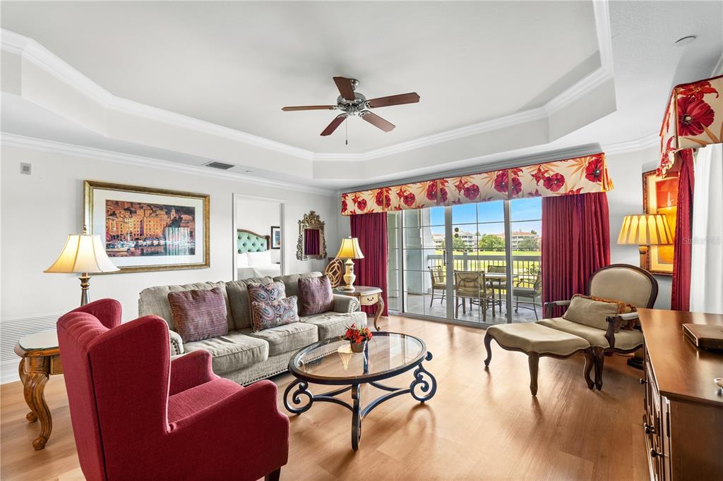 A living room features a red armchair, a sofa, a glass coffee table, and balcony access — 1100 SUNSET VIEW CIRCLE UNIT 204, REUNION, FL