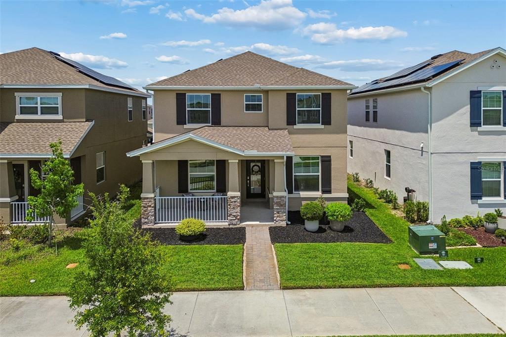 A two-story suburban house with a front porch, stone accents, and a paved walkway — 9745 INTRODUCTION WAY, ORLANDO, FL