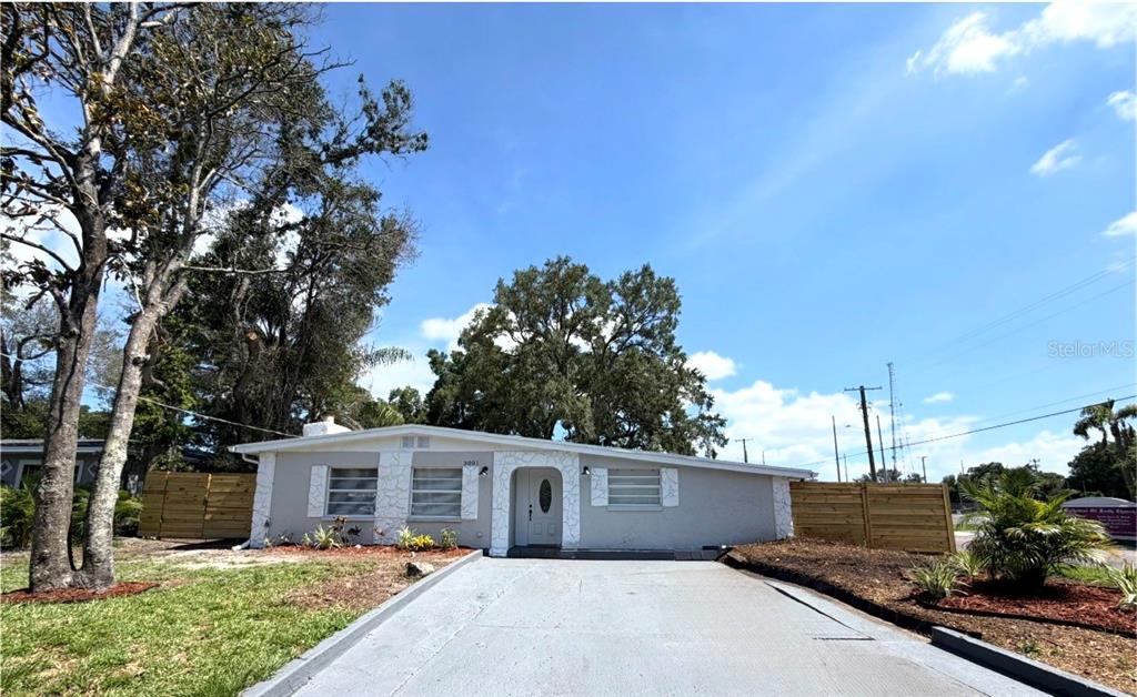 A single-story house with a gray exterior, a concrete driveway, and a wooden fence — 3001 E FERN STREET, TAMPA, FL