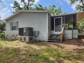 The exterior of a light-colored manufactured home features a screened porch and an HVAC unit — 5550 S CORAL BELLS AVENUE, HOMOSASSA, FL