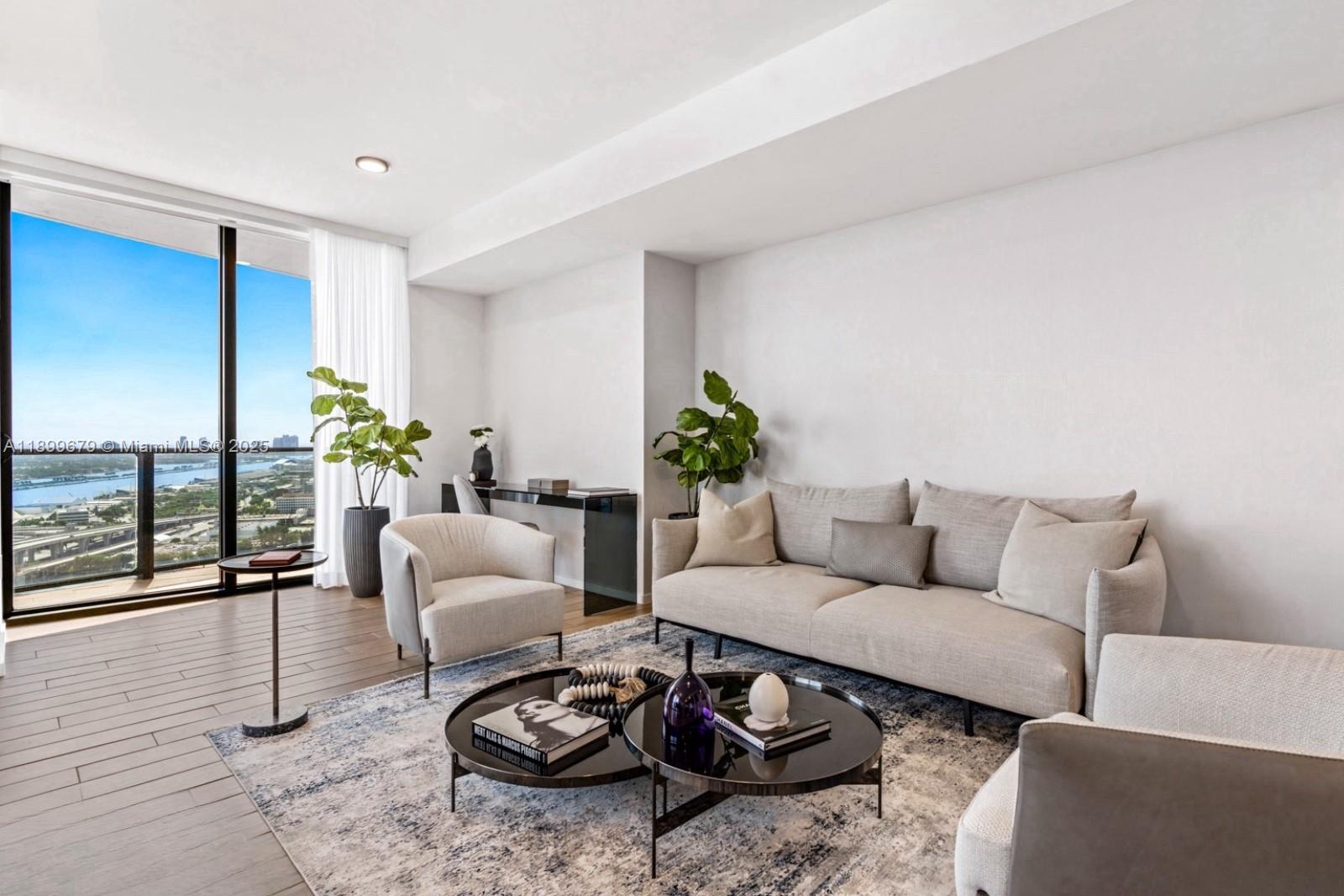A modern living room features a sofa, armchairs, coffee tables, and a view of the city — 398 NE 5th St # 4409, Miami FL 33132, MIAMI, FL