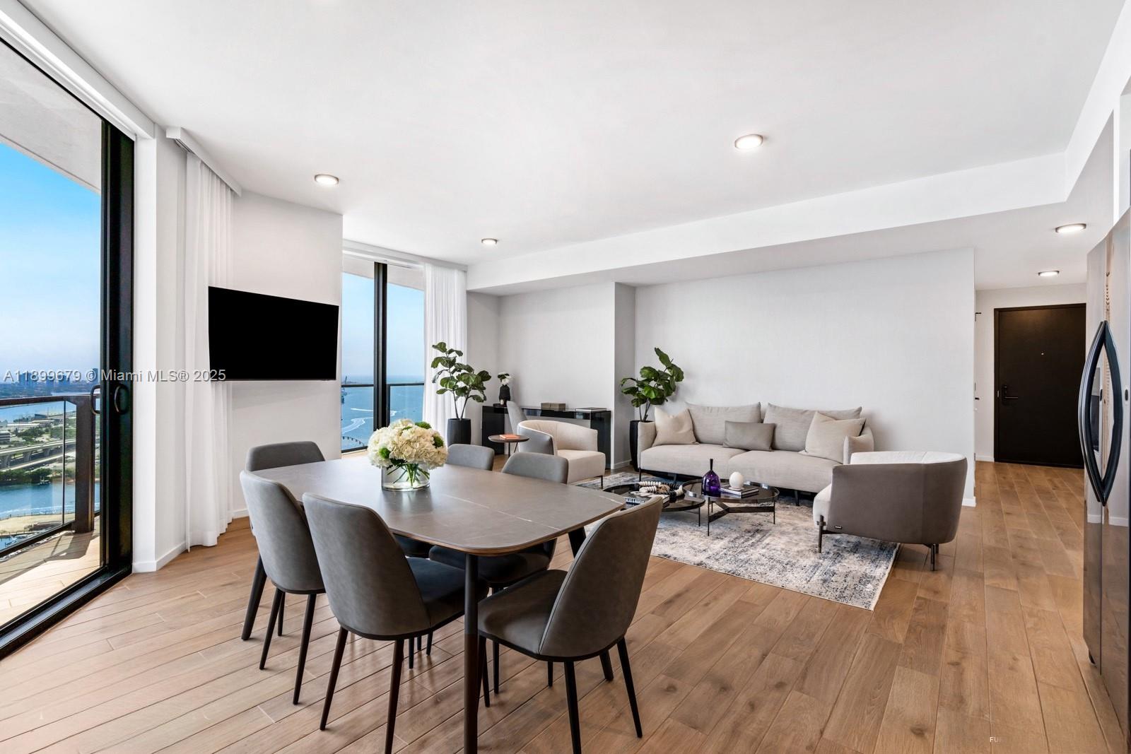 A modern living and dining area features hardwood floors, floor-to-ceiling windows, and ocean views — 398 NE 5th St # 4409, Miami FL 33132, MIAMI, FL
