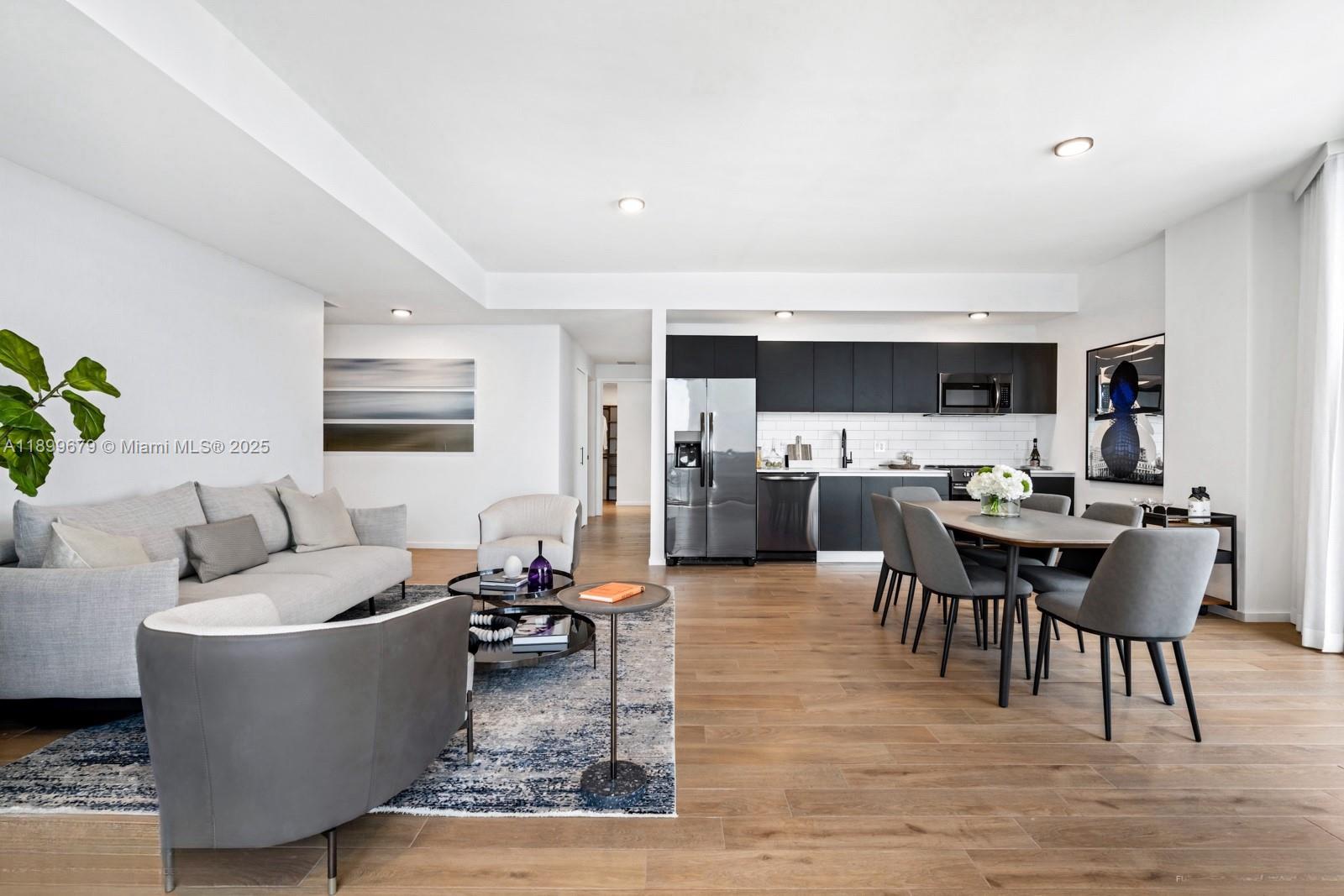 An open-concept living and dining area features light wood floors and a modern black kitchen — 398 NE 5th St # 4409, Miami FL 33132, MIAMI, FL