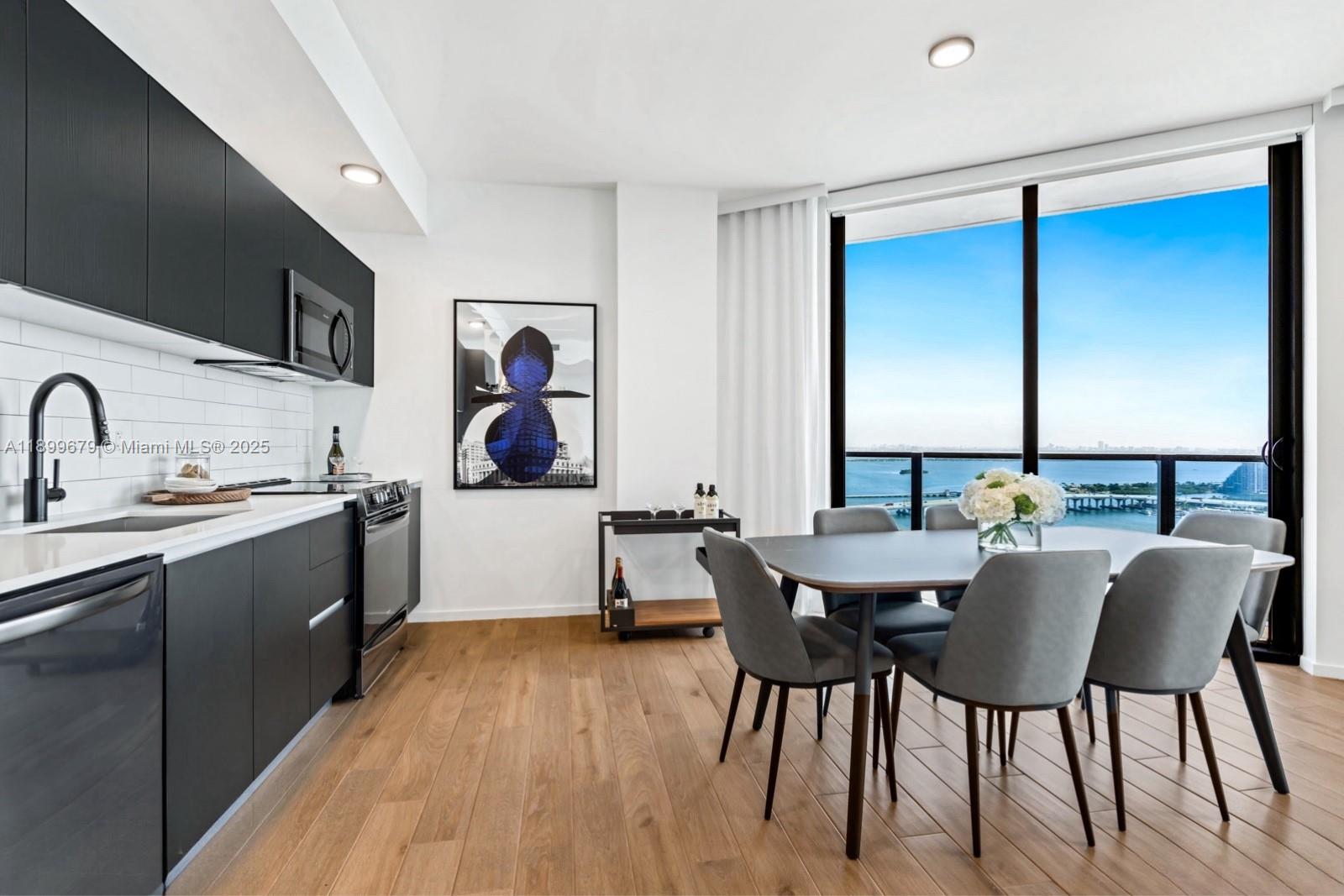 A modern kitchen and dining area feature dark cabinetry, wood flooring, and floor-to-ceiling windows — 398 NE 5th St # 4409, Miami FL 33132, MIAMI, FL