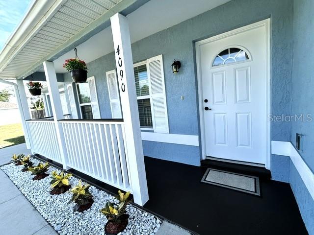 A blue house exterior features a white front door, a porch with railings, and landscaping — 4090 SW 167TH STREET, OCALA, FL