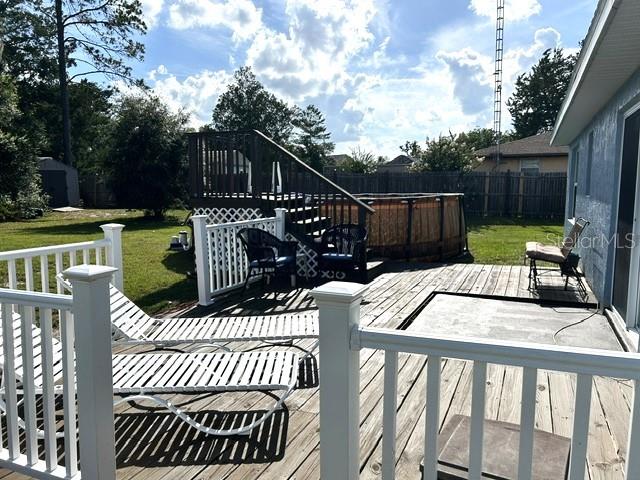 A wooden deck features white railings, lounge chairs, and an above-ground pool in the backyard — 4090 SW 167TH STREET, OCALA, FL