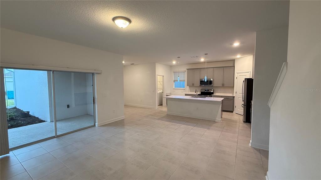 An open-concept kitchen with a central island and sliding glass doors leading to a patio — 11830 LANGUAGE WAY, ORLANDO, FL