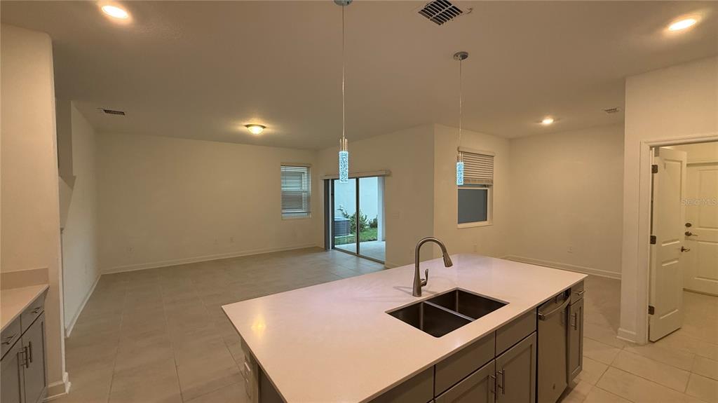 A kitchen island with a double sink sits in an open-concept room with tile flooring — 11830 LANGUAGE WAY, ORLANDO, FL