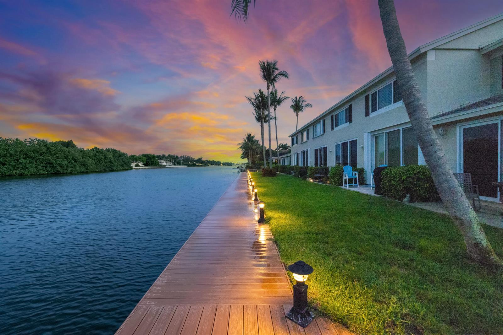 A wooden dock with path lights runs alongside a grassy lawn and waterfront townhomes — 809 Kokomo Key Lane, Delray Beach FL 33483, DELRAY BEACH, FL