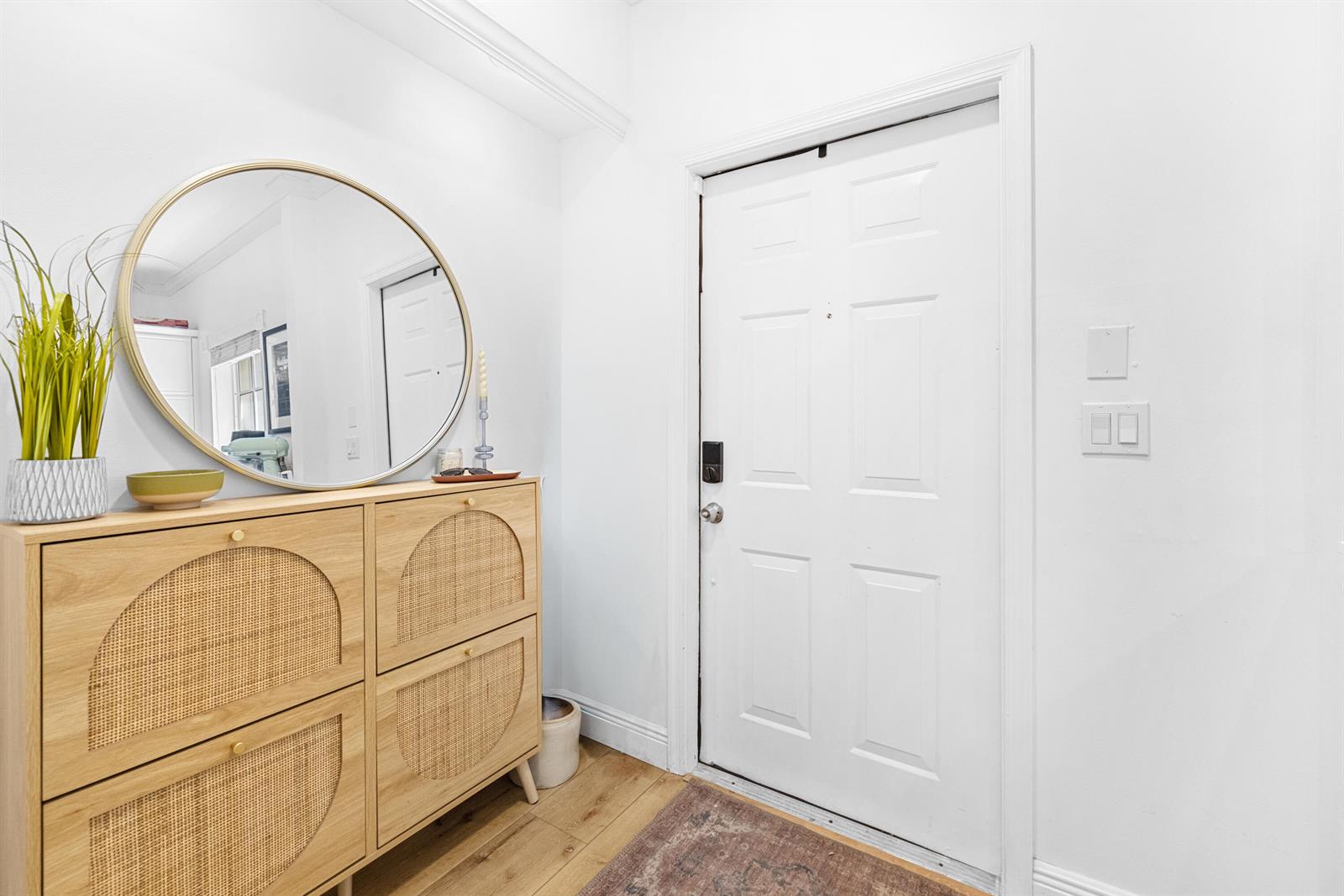 An entryway features a light wood cabinet, a round mirror, and a white door — 809 Kokomo Key Lane, Delray Beach FL 33483, DELRAY BEACH, FL