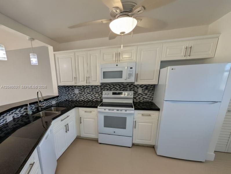 A kitchen features white cabinets, black countertops, a tiled backsplash, and white appliances — 1750 NE 191st St # 3, Miami FL 33179, MIAMI, FL