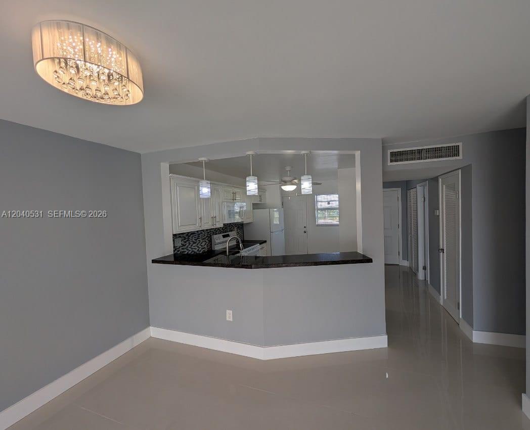 A kitchen with white cabinets and a dark countertop opens into a dining area — 1750 NE 191st St # 3, Miami FL 33179, MIAMI, FL
