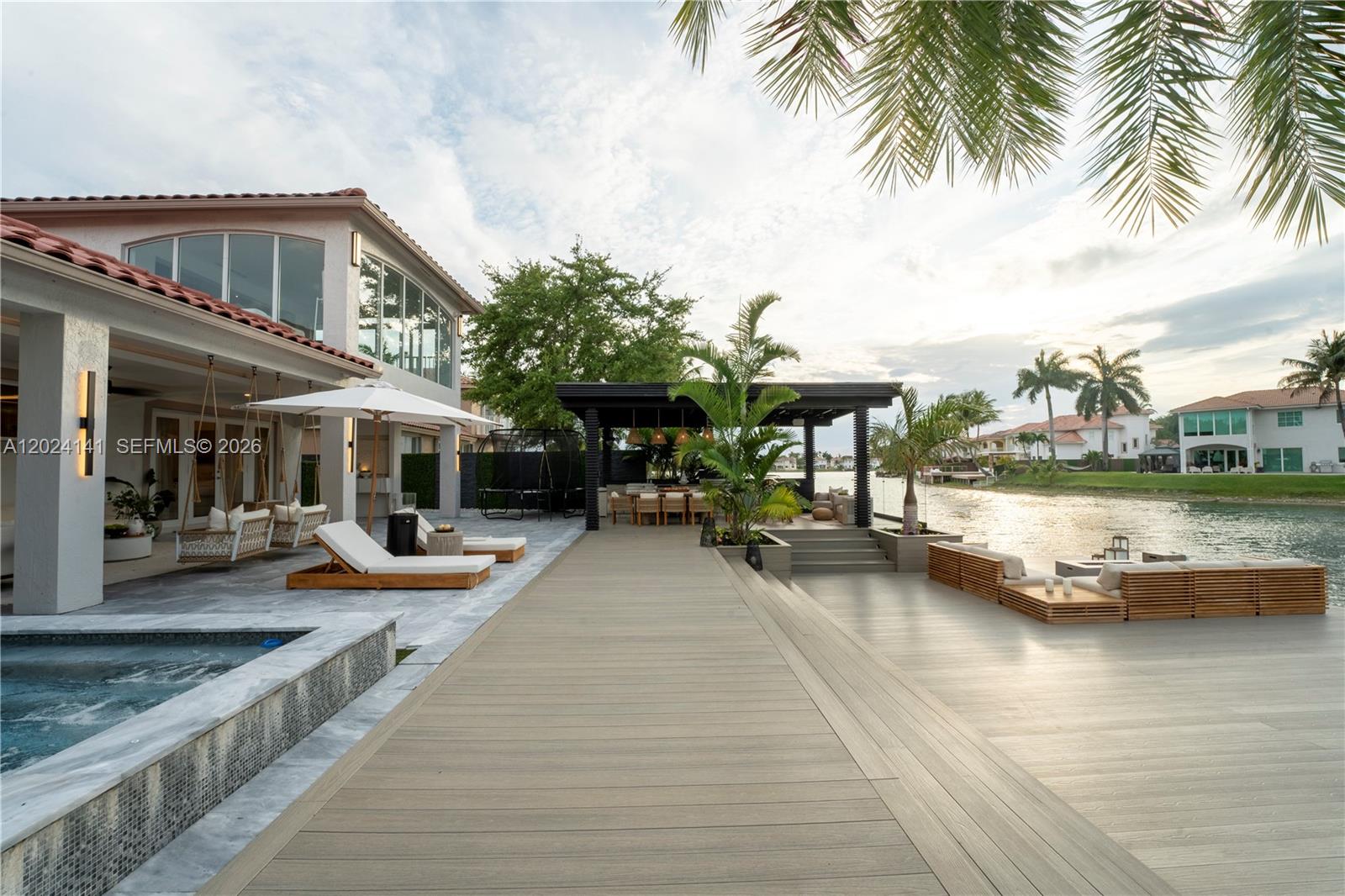 A waterfront patio features a wooden deck, a covered dining area, and a swimming pool — DORAL, FL