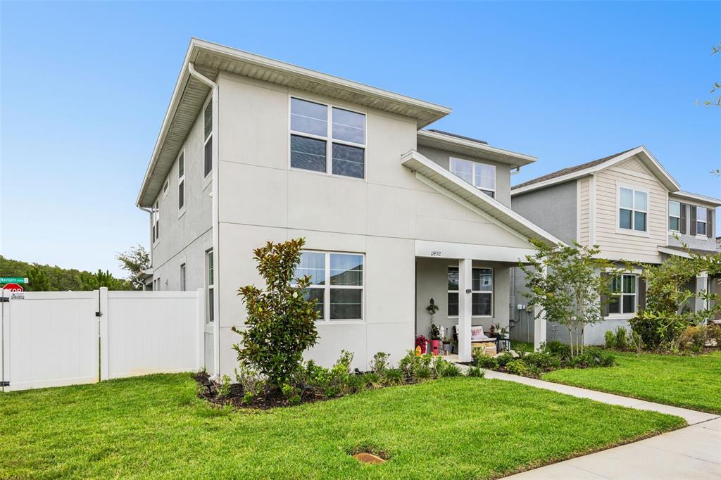 A two-story house with a white exterior, a covered front porch, and a white fence — 11492 SUNSAIL AVENUE, ORLANDO, FL