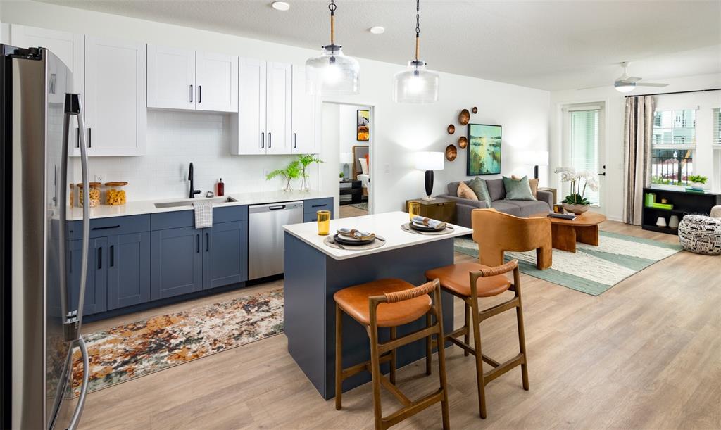 A modern kitchen with blue and white cabinets opens into a living room with furniture — 14370 FL-64 ROAD UNIT C1.1, BRADENTON, FL