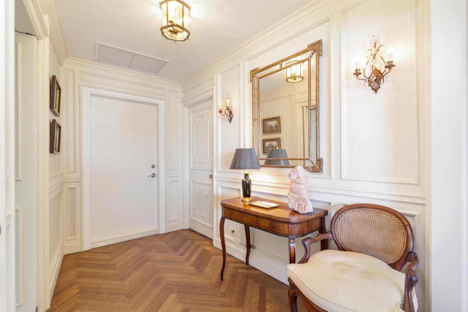 A classic foyer features herringbone wood floors, white wainscoting, a console table, and a mirror — 389 S Lake Drive, Palm Beach FL 33480, PALM BEACH, FL
