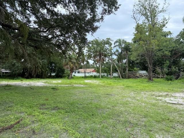 A grassy, partially cleared lot features scattered trees and shrubs under an overcast sky — 200 11TH AVENUE E, BRADENTON, FL