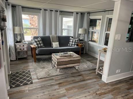 A living room features a grey futon, a wooden crate coffee table, and wood-look flooring — 3803 116TH STREET COURT W, BRADENTON, FL