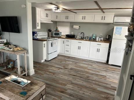 A kitchen with white cabinets, wood-look flooring, and a white refrigerator in an open space — 3803 116TH STREET COURT W, BRADENTON, FL