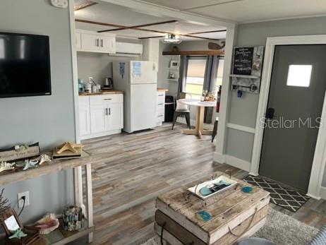 An open-concept living area features a kitchen with white cabinets, a refrigerator, and wood-look flooring — 3803 116TH STREET COURT W, BRADENTON, FL