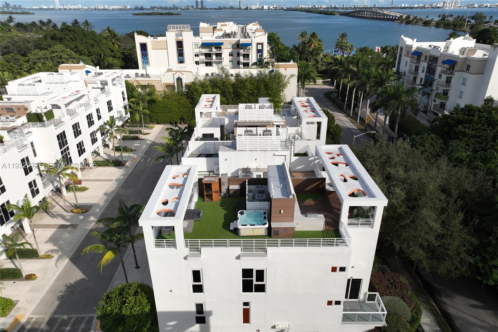 An aerial view shows a white multi-story building with a rooftop terrace featuring a hot tub — 455 NE 39th St # 202, Miami FL 33137, MIAMI, FL