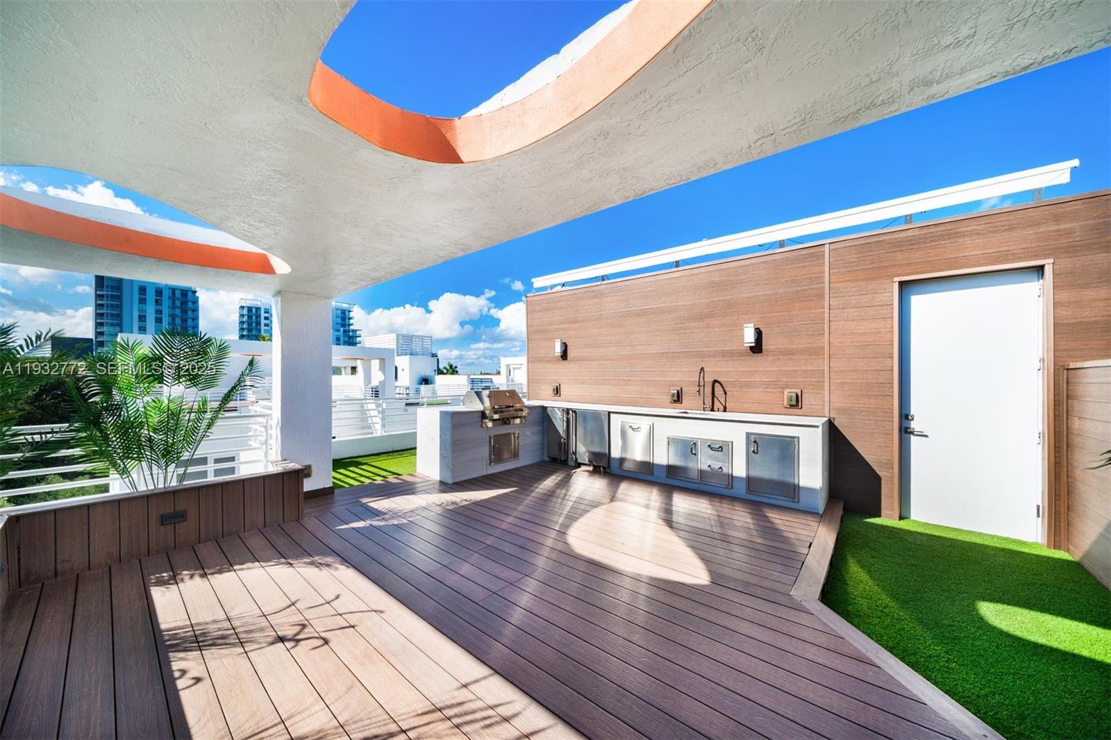 A rooftop deck features a wooden floor, an outdoor kitchen, and a partial concrete roof — 455 NE 39th St # 202, Miami FL 33137, MIAMI, FL
