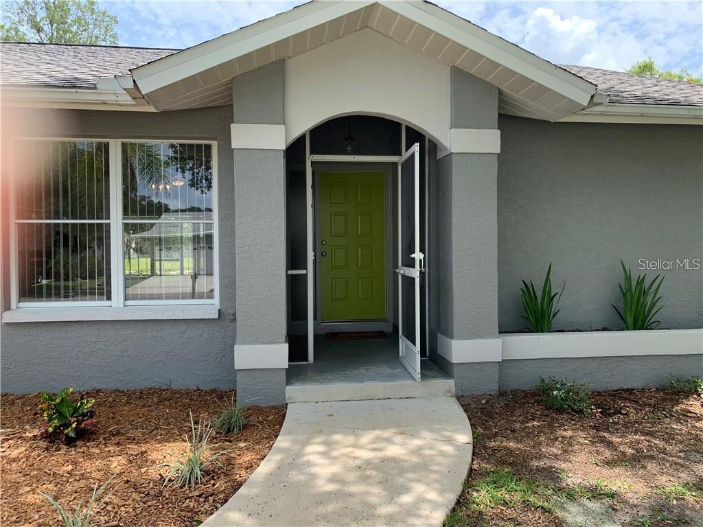 The exterior of a gray house features a lime green front door and a walkway — 2193 CORK OAK STREET E, SARASOTA, FL