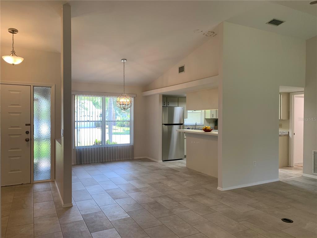 A dining area with tile floors and a pendant light sits beside a kitchen — 2193 CORK OAK STREET E, SARASOTA, FL