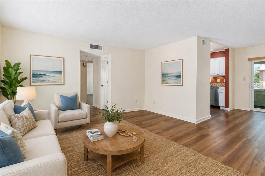 A living room features a beige sofa, a round coffee table, and light wood flooring — 7001 PLACE DE LA PAIX UNIT 2A, SOUTH PASADENA, FL